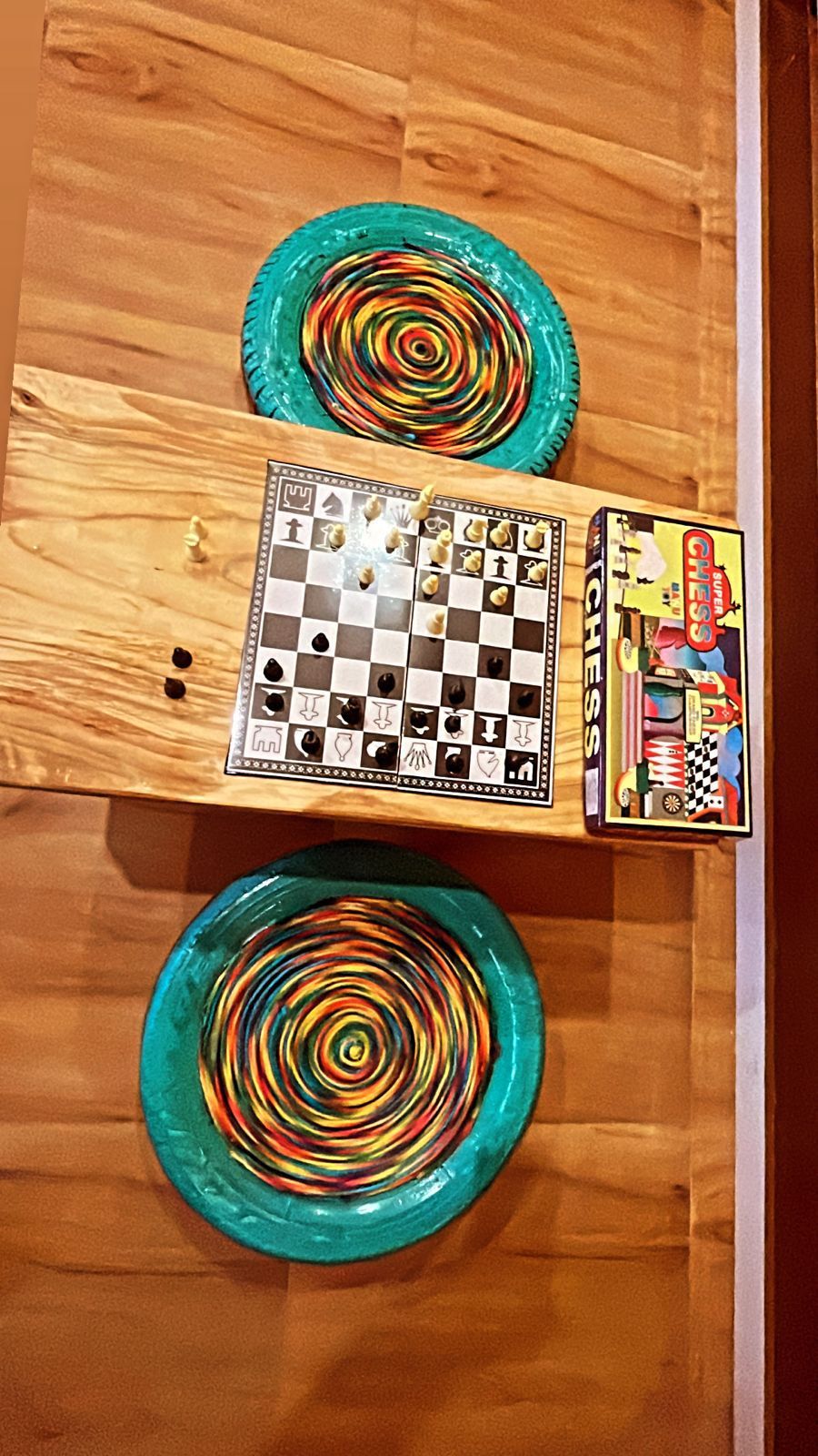 A wooden table with a chessboard and two colorful spiral glass plates.
