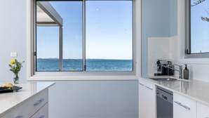 A modern kitchen with a large window overlooking a body of water and distant land.