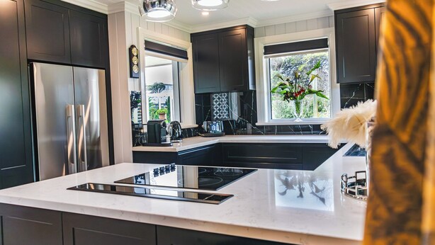 A modern kitchen with dark cabinets, stainless steel appliances, a central island, and pendant lighting. - Lore Haven - Your little slice of paradise (Robe)