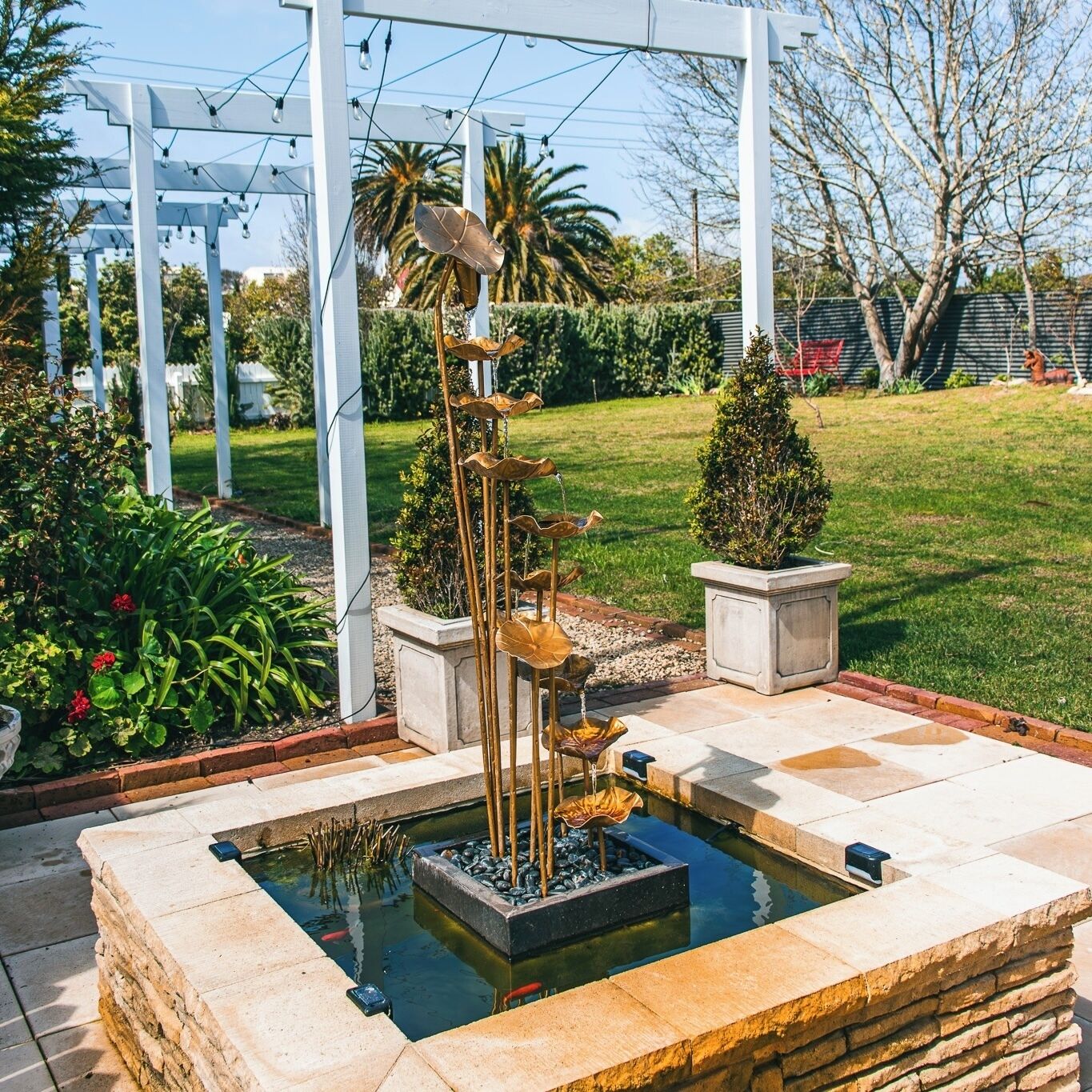 Ein Garten mit Teich für Koi-Karpfen, einer Pergola und einer kleinen Weihnachtstanne.