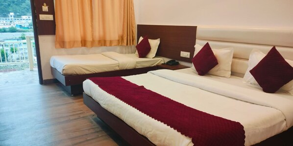 A hotel room with two beds, a wooden floor, a view of the outside, and a window with curtains. - Pride Inn Luxury Resort (Yamkeshwar)
