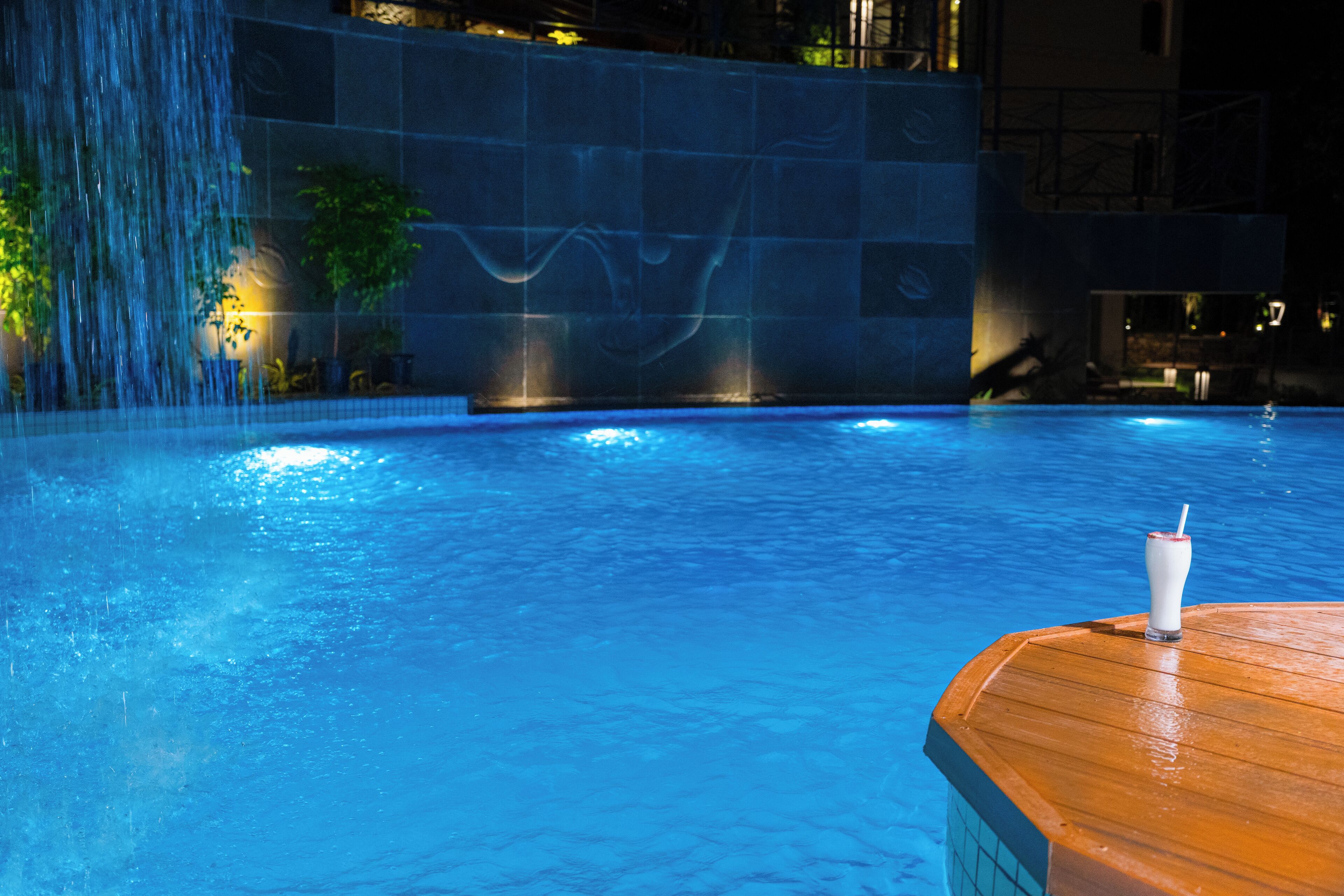 A pool with a wooden deck and a waterfall feature.