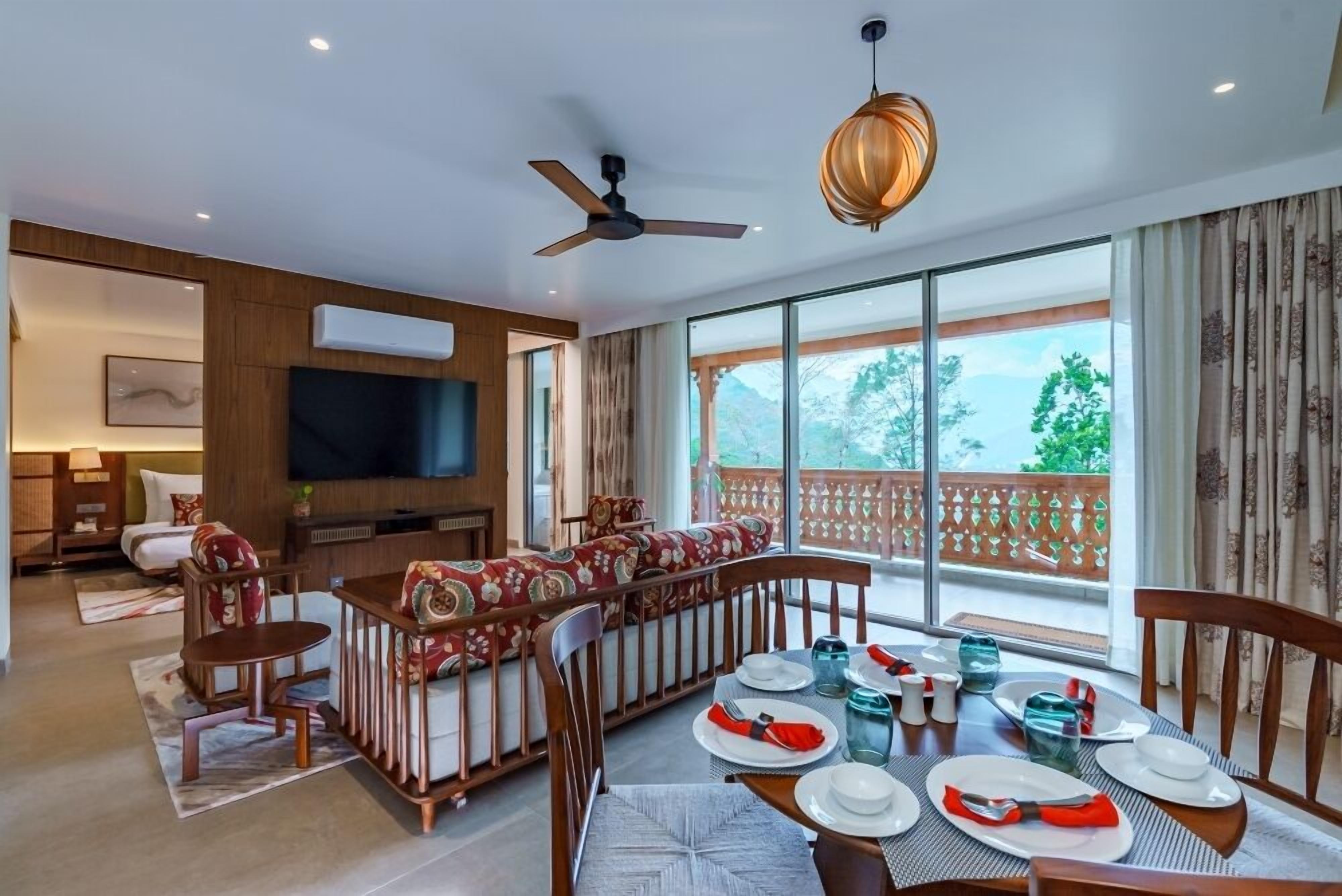 A modern living room with a dining area, large windows, and a ceiling fan.