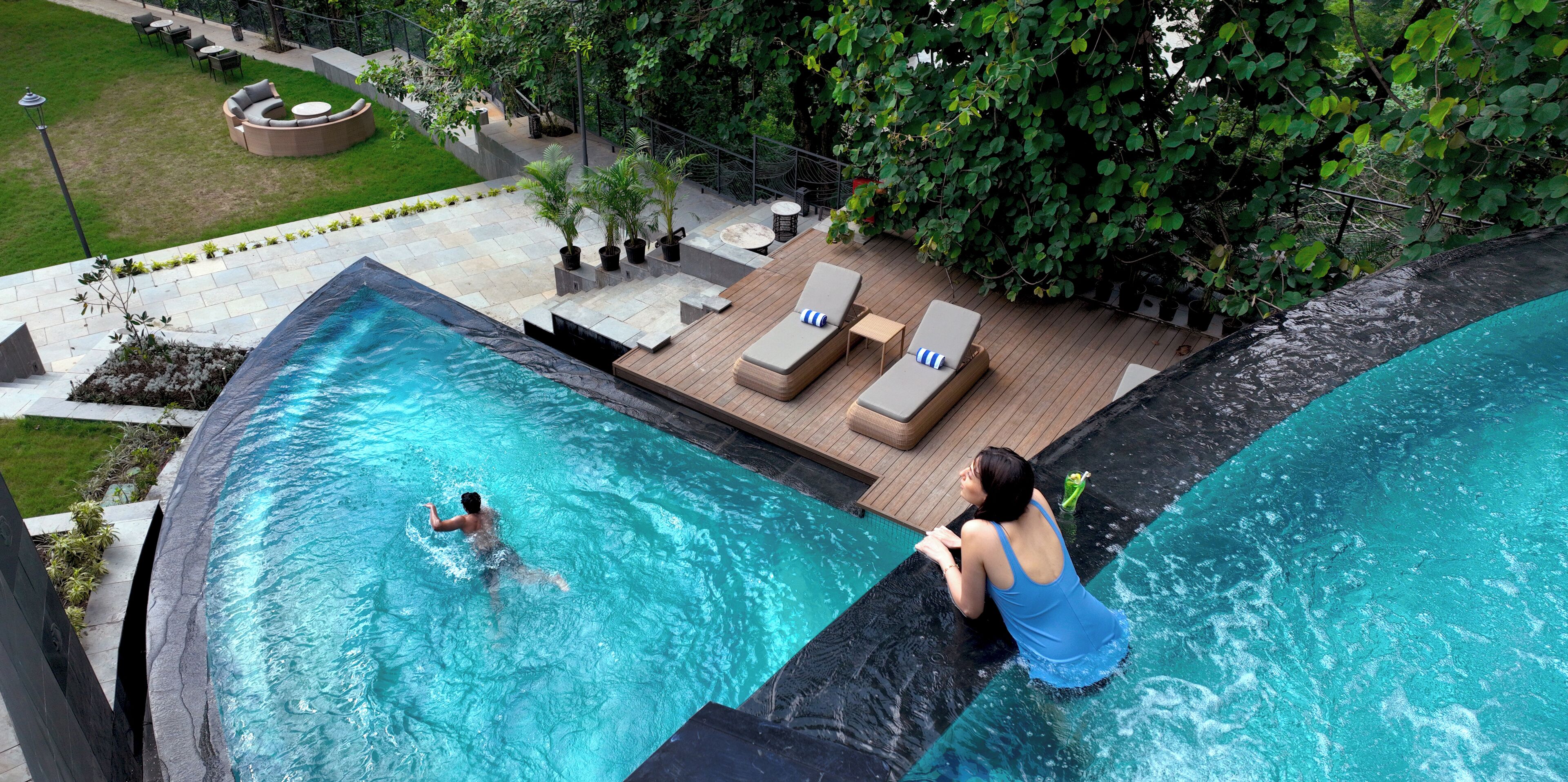 A rooftop infinity pool with a view of the city, a lounge area with seating, and a small garden.