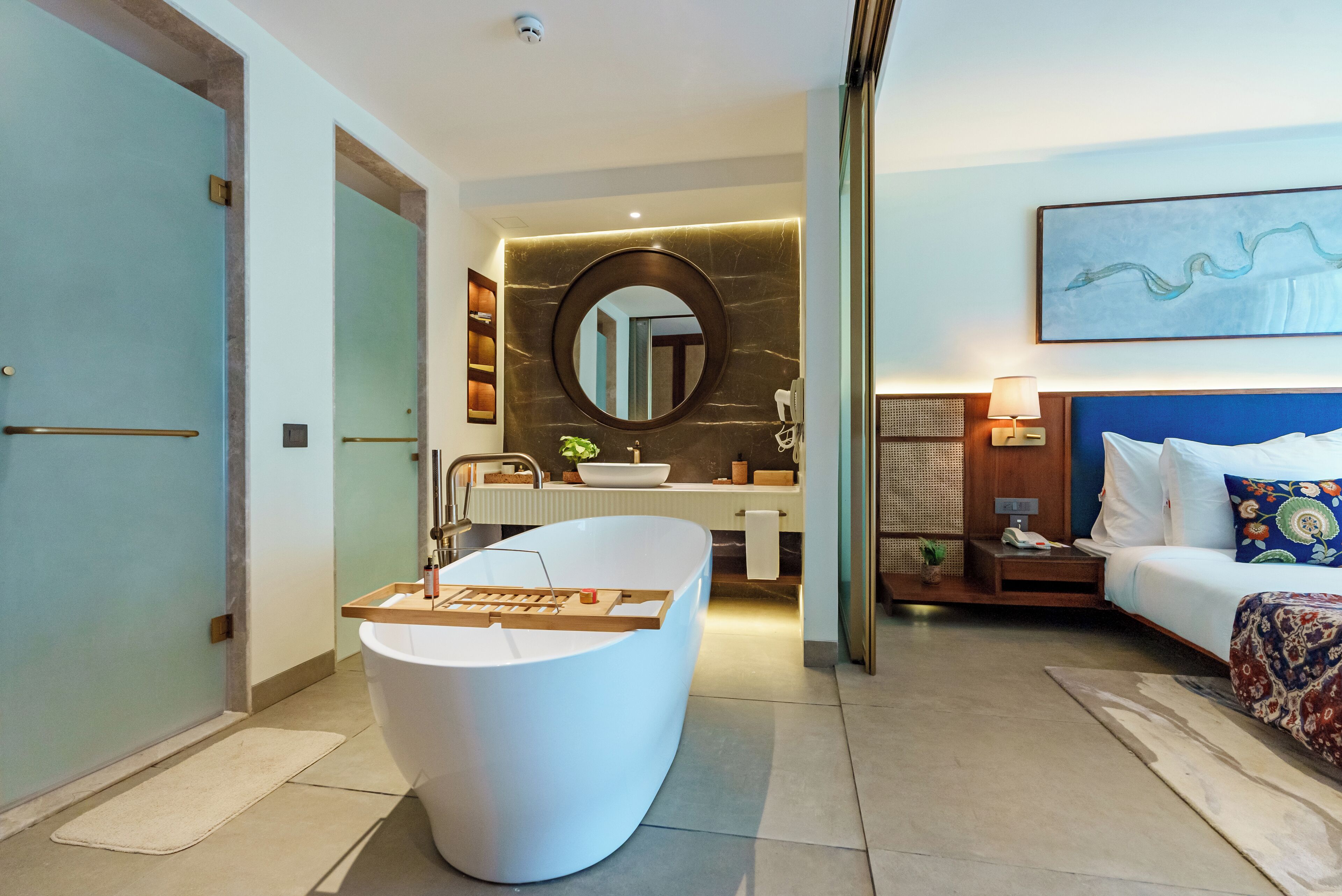 A modern bathroom with a freestanding bathtub, a round mirror, and a sink.
