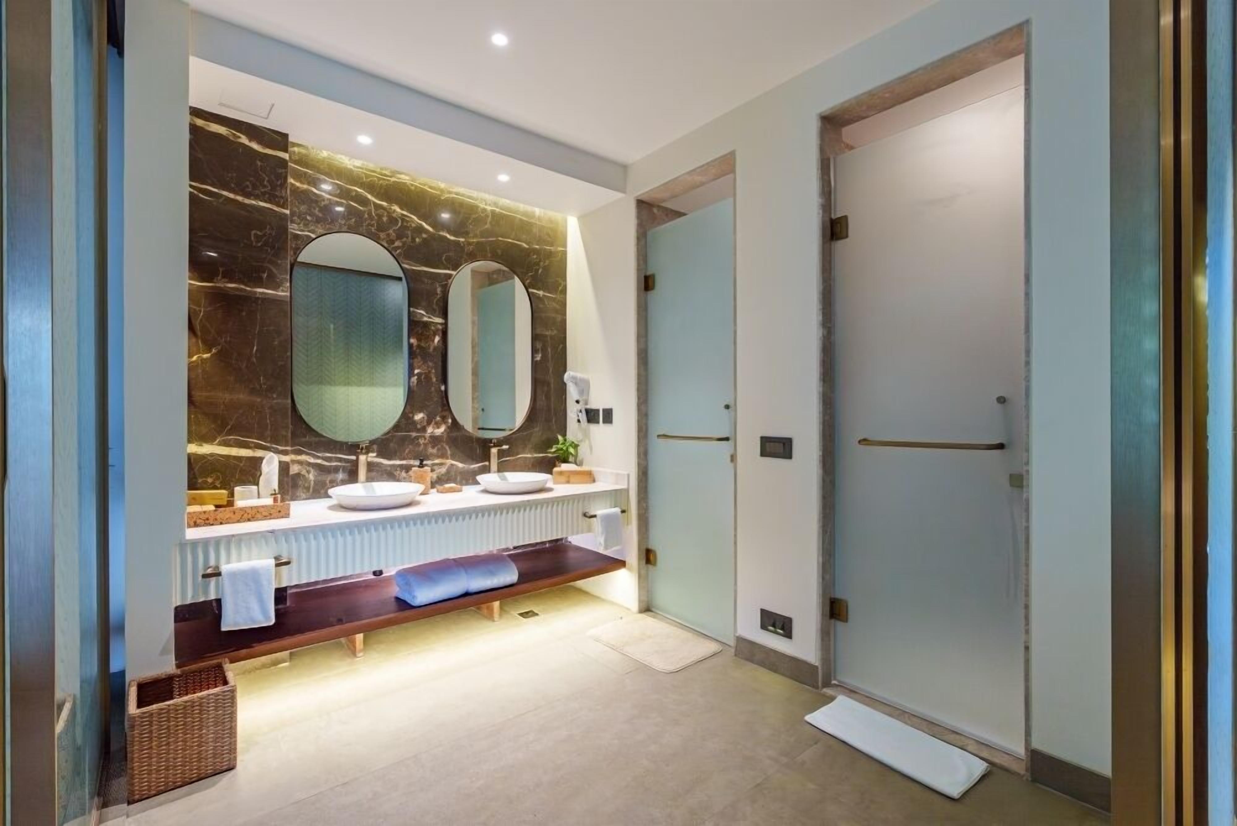 A modern bathroom with a marble backsplash, two mirrors, a vanity with a sink, and a shower area.