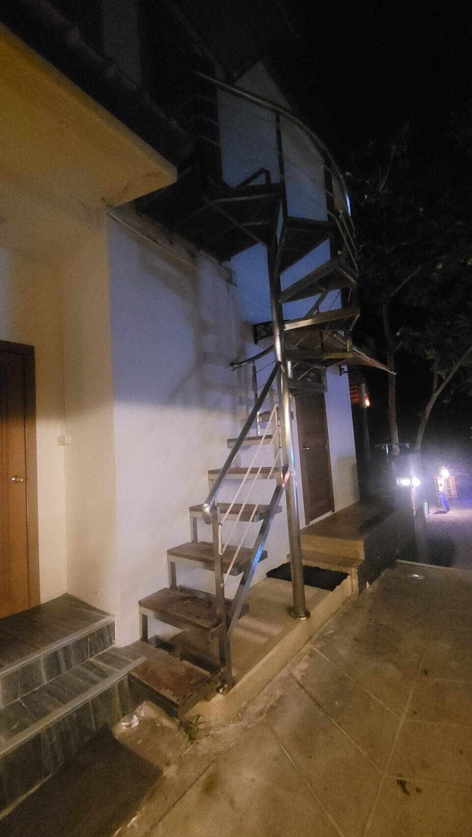 A staircase leading to a door, with a metal railing and a tiled floor.