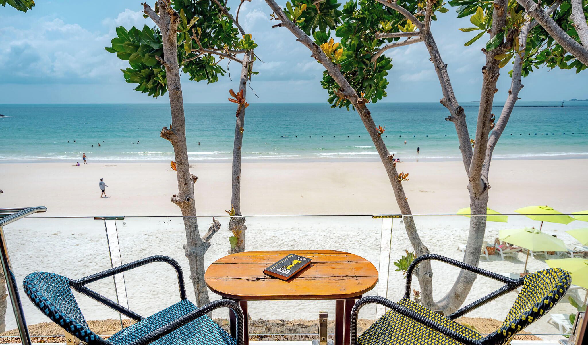 A beachside seating area with a table and chairs, overlooking the ocean.
