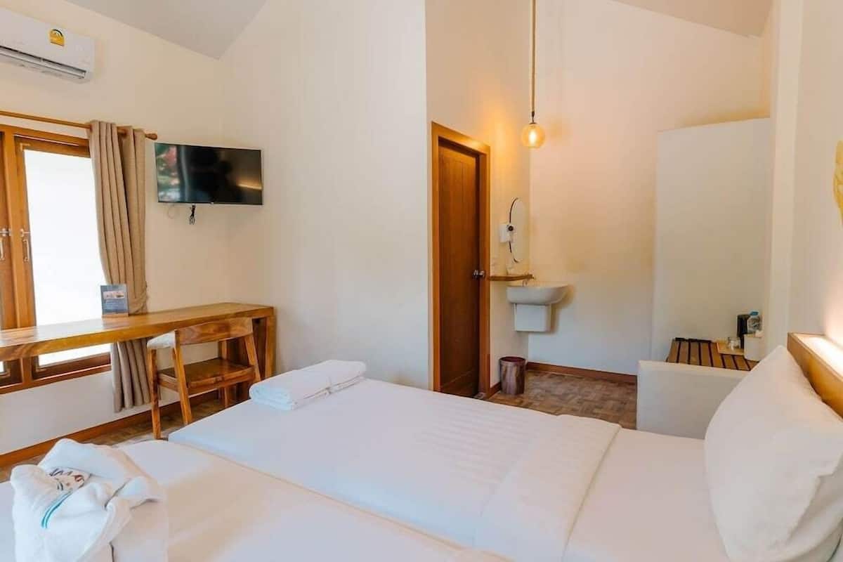 A hotel room with a bed, a desk, a TV, a sink, and a mirror.