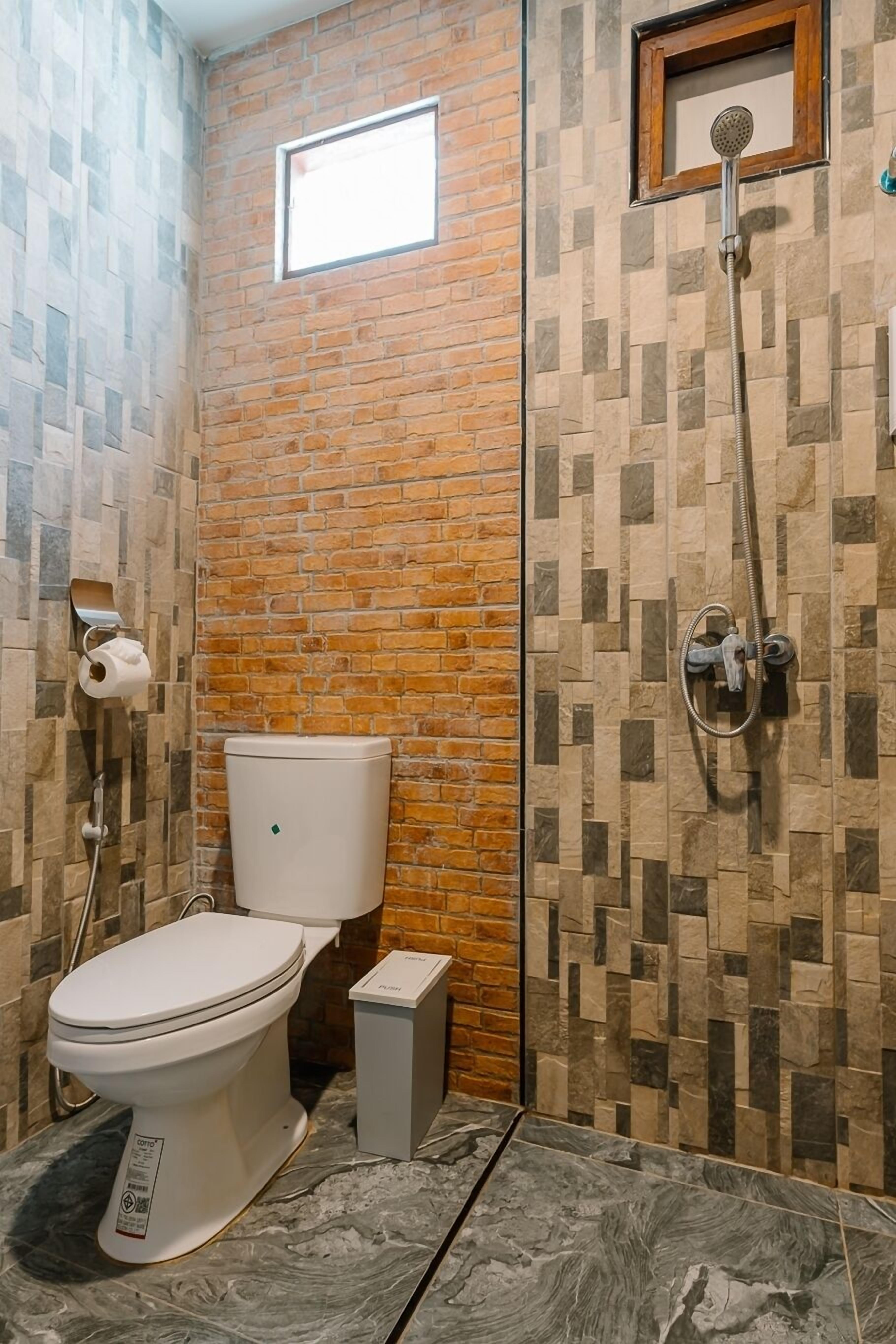 Un baño con inodoro, ducha y un ventanal pequeño.