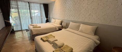 A hotel room with two beds, white linens, and a brick wall.
