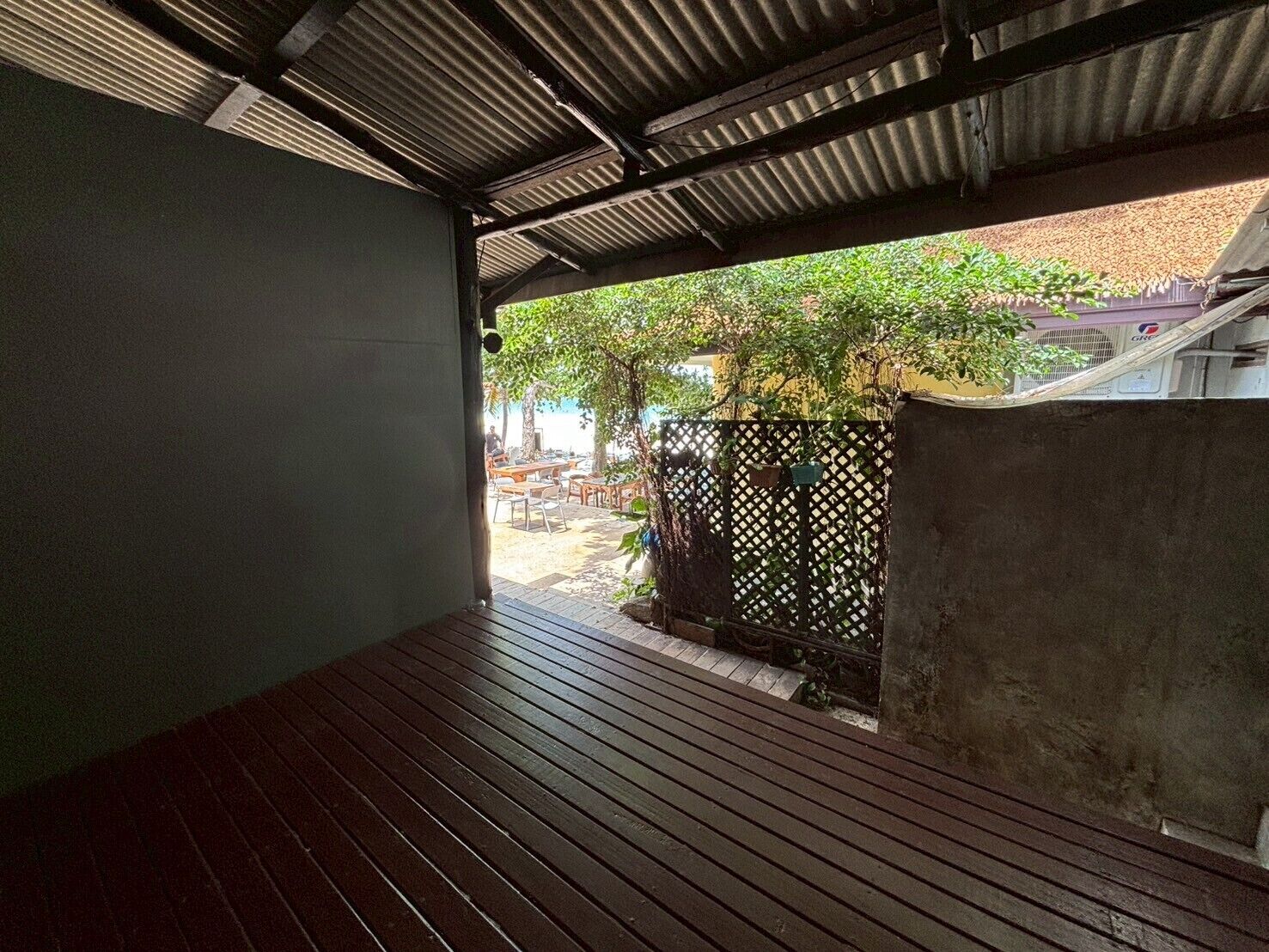 Un patio al aire libre con suelo de madera y techo de metal.