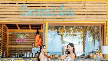 A wooden bar with a tropical theme, including tiki totems and a neon sign reading "Coconut bar".