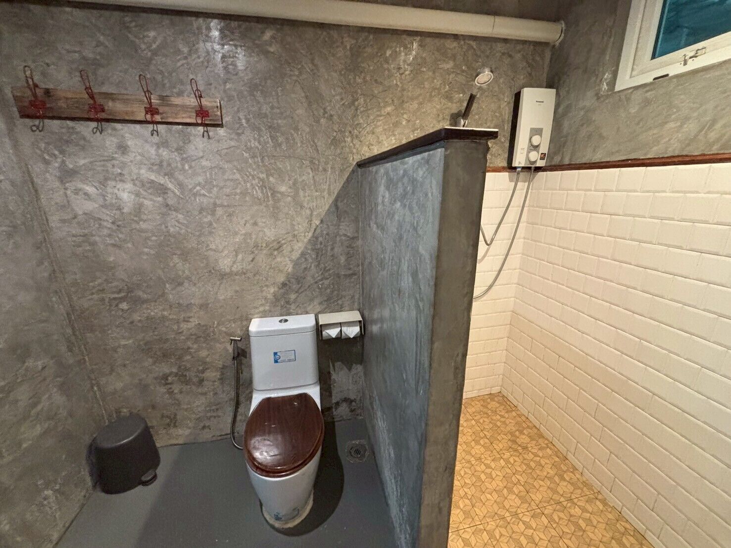 A small, enclosed bathroom with a toilet, a hand dryer, and a towel rack.