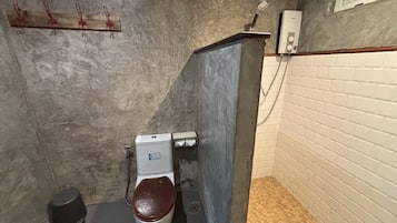 A small, enclosed bathroom with a toilet, a hand dryer, and a towel rack.