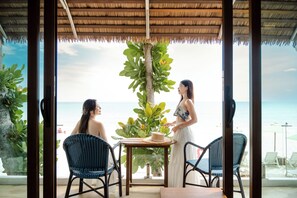 Habitación con vista al mar, que incluye una mesa con sillas, una planta y una sombrilla de playa.