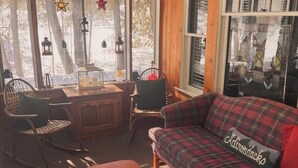 A cozy living room with a plaid sofa, rocking chairs, a wooden coffee table, and a fireplace.