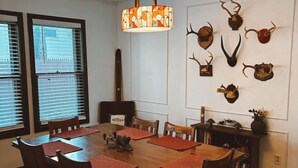 A dining room with a wooden table, red placemats, and a chandelier.