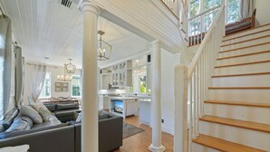 A spacious living area with a gray sectional sofa, wooden flooring, and a staircase with white columns. - 377 Ft. to Beach in Seaside, By Pool, Sleeps 18 + 2 Adult Bikes! (Santa Rosa Beach)