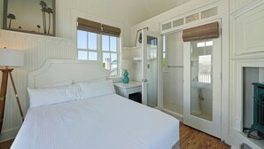 A bedroom with a bed, a nightstand, a lamp, a window with blinds, a door leading to a bathroom, and a painting on the wall. - 377 Ft. to Beach in Seaside, By Pool, Sleeps 18 + 2 Adult Bikes! (Santa Rosa Beach)