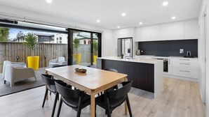 Una cocina moderna con armarios blancos, una isla central y un comedor con una mesa de madera y sillas negras.