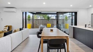 Una sala moderna con sofá, mesa de comedor, sillas y zona de cocina.