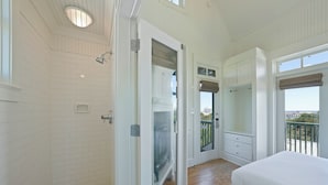 Une chambre avec un grand lit, un dressing et une salle de bain avec douche.