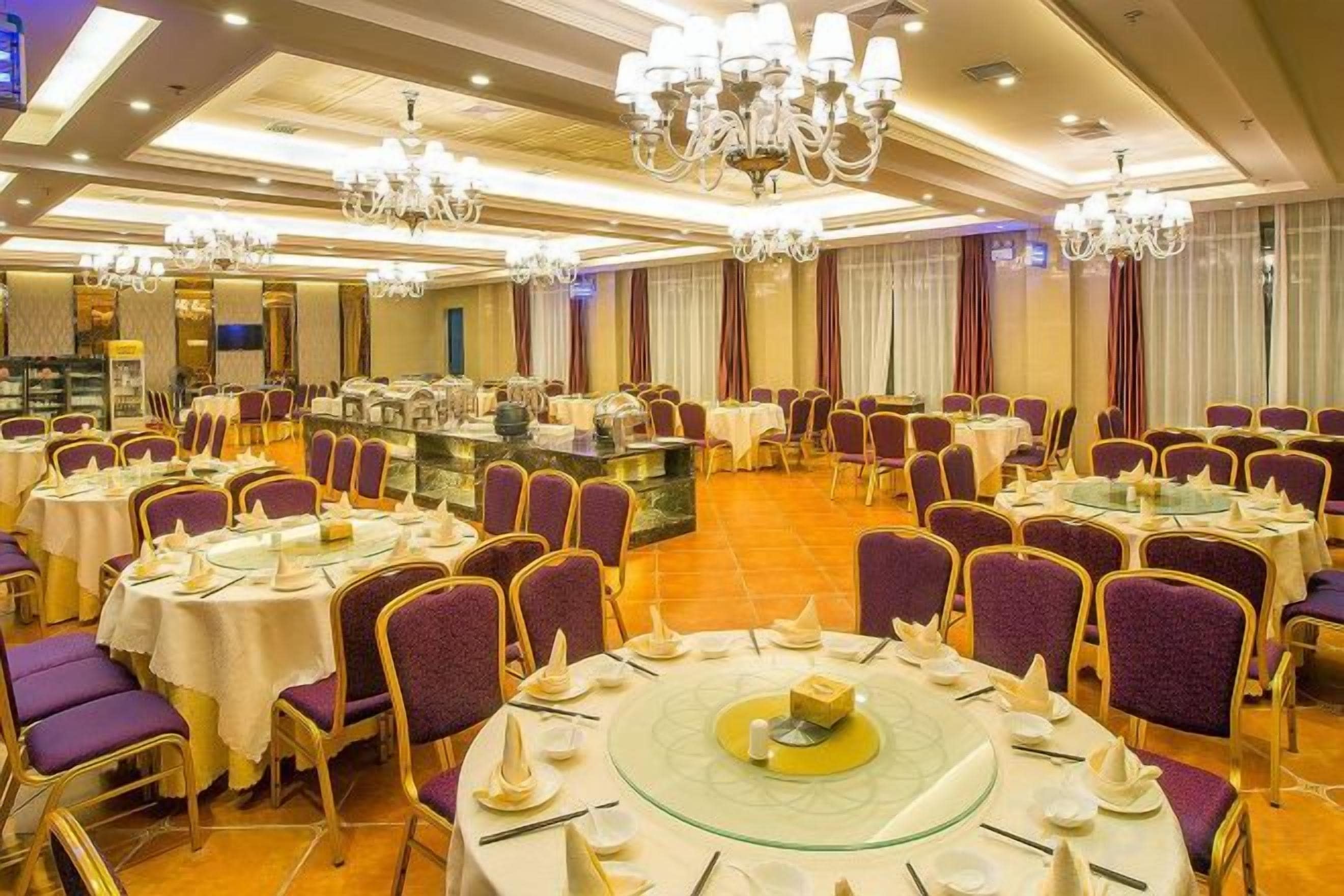 Un salón de banquetes con mesas redondas, sillas moradas y candelabros.