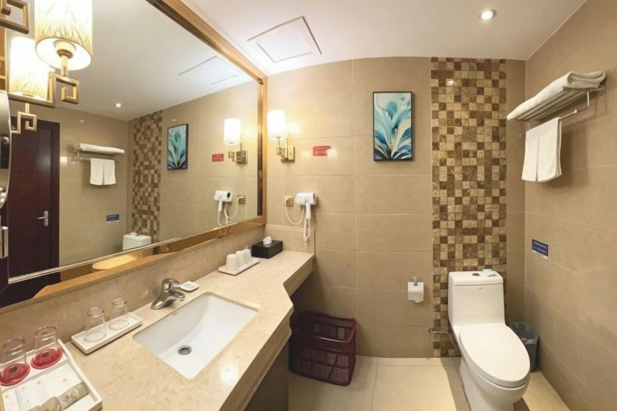 A bathroom with a sink, mirror, toilet, and a wall-mounted towel rack.