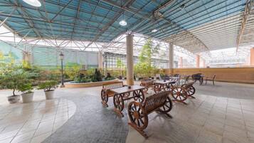 An indoor patio area with tables and benches, potted plants, and a covered roof structure.