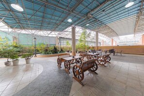 An indoor patio area with tables and benches, potted plants, and a covered roof structure. - Yiyang Hotel (Yiling Wanda Plaza, Yichang Three Gorges Enterprise Base) (Yichang)