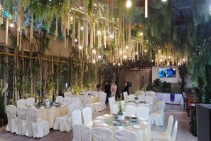 A banquet hall with round tables, white chairs, and hanging plants. - Yiyang Hotel (Yiling Wanda Plaza, Yichang Three Gorges Enterprise Base) (Yichang)