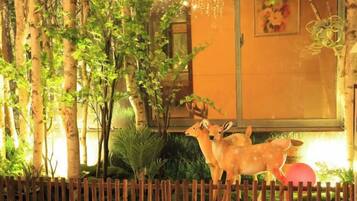 A decorative outdoor area with a wooden fence, trees, and a statue of deer.