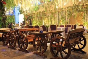 Outdoor seating with wooden tables and benches, surrounded by hanging plants and greenery. - Yiyang Hotel (Yiling Wanda Plaza, Yichang Three Gorges Enterprise Base) (Yichang)