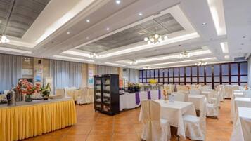 A banquet hall with round tables, a buffet area, and a stage.