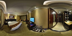Een hotelkamer met een bed, televisie, zithoek en een spiegel.