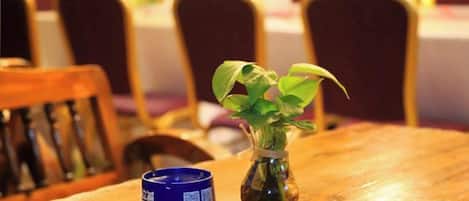 Una mesa de madera con un pequeño jarrón de plantas verdes y un objeto azul.