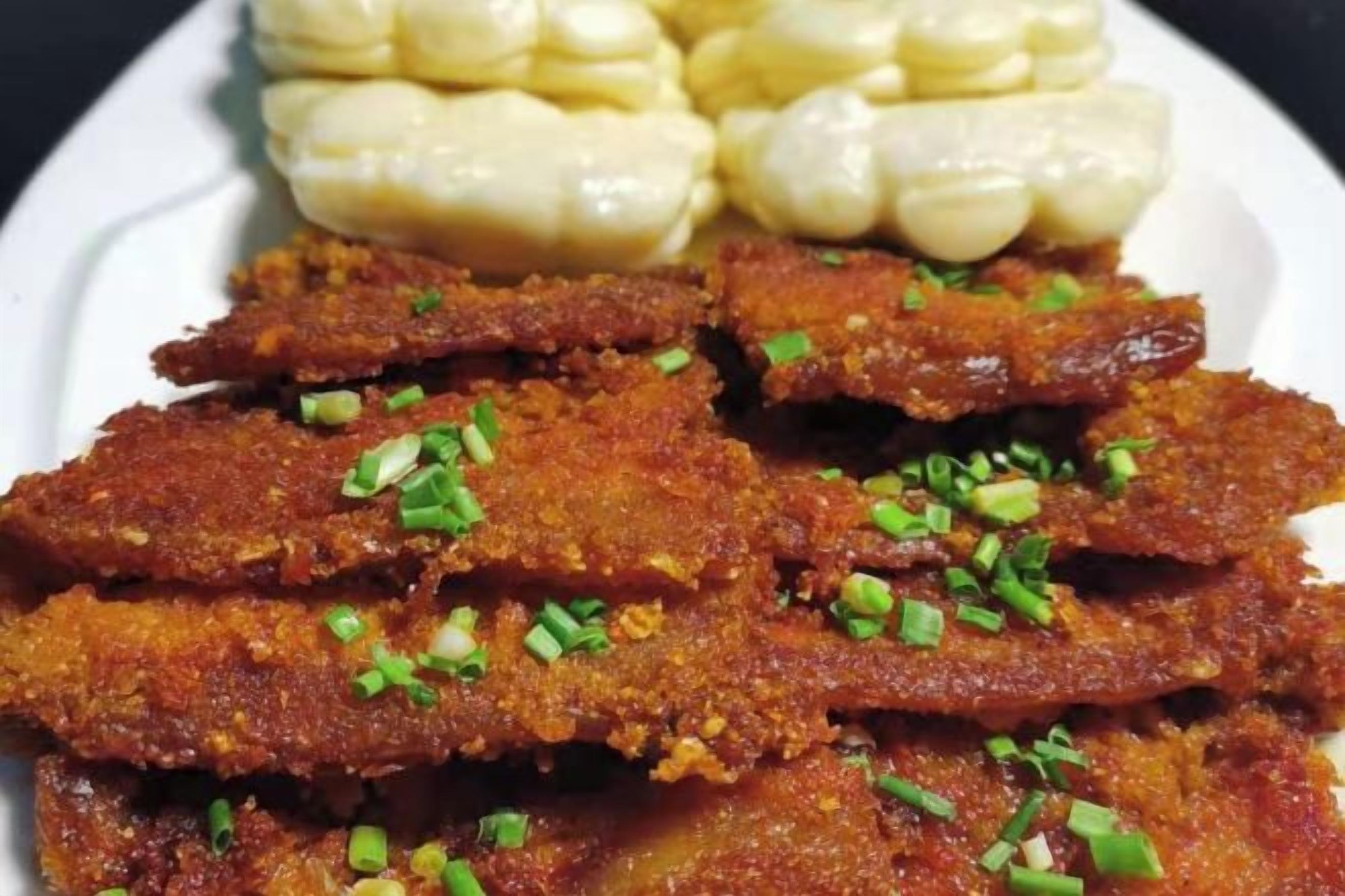 A plate with fried fish and corn on the cob.