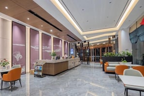 Un vestíbulo de hotel con mostrador de recepción, zona de estar y un ventanal grande.