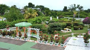 A lush garden with a gazebo, potted plants, and a white fence. - Villa Ludivine 2 (Sainte-Anne, Guadeloupe)
