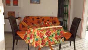 A dining area with a table covered by a colorful tablecloth, two chairs, and a sofa. - Villa Ludivine 2 (Sainte-Anne, Guadeloupe)