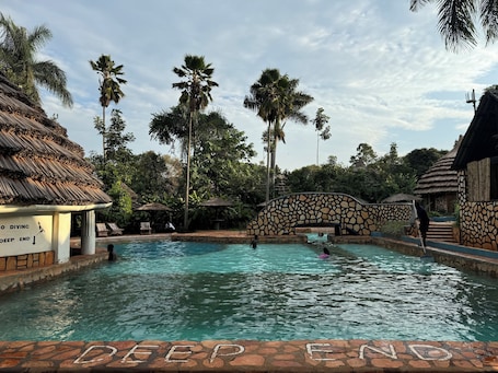 Una piscina al aire libre, sillones reclinables de piscina