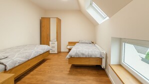 Une chambre avec deux lits, une armoire, un radiateur et une fenêtre donnant sur un beau paysage.