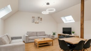 Un salon moderne comprenant un canapé, une table basse et un espace télévision avec un meuble TV en bois.