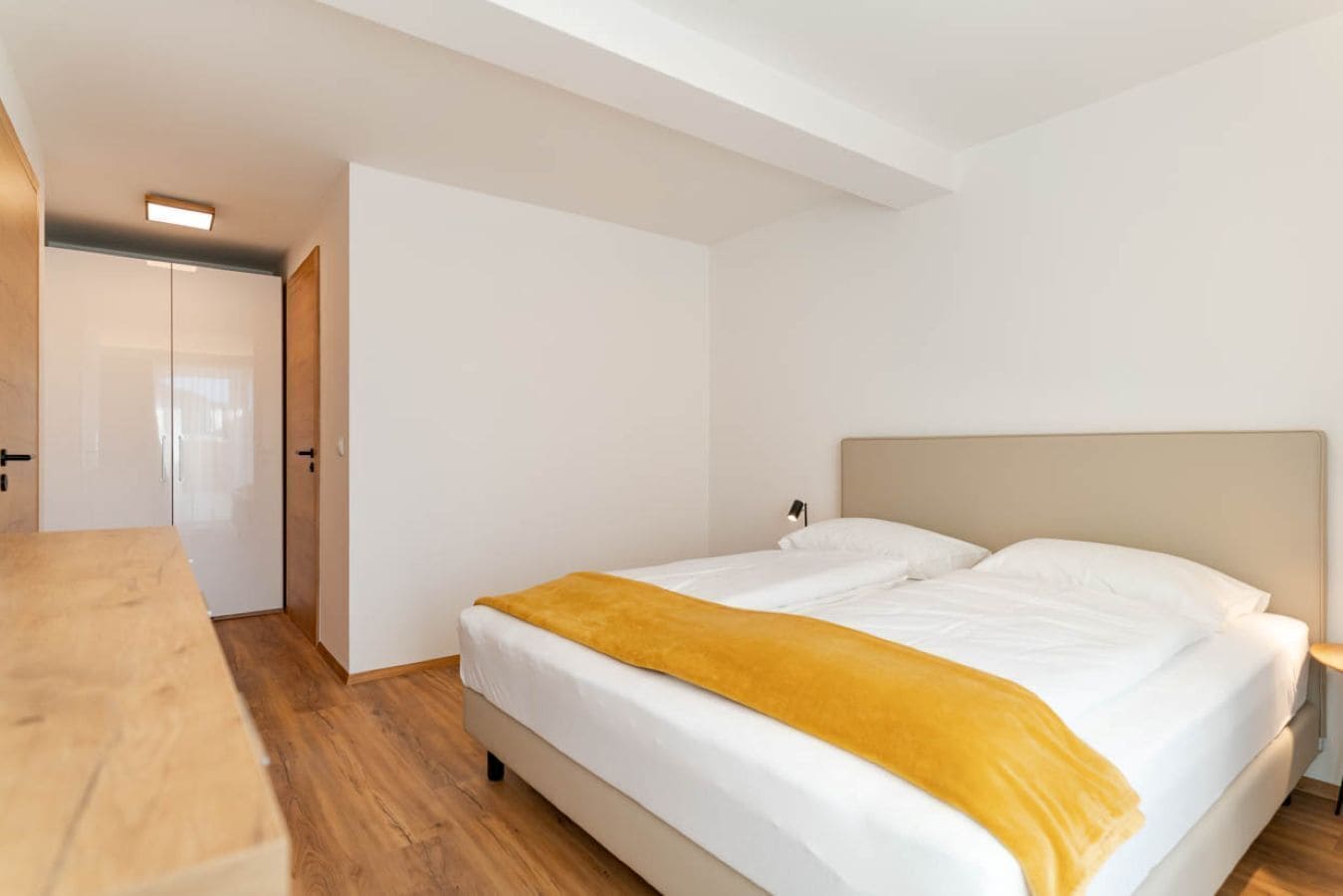A bedroom with a bed, a bedside table, a nightstand, and a wardrobe.