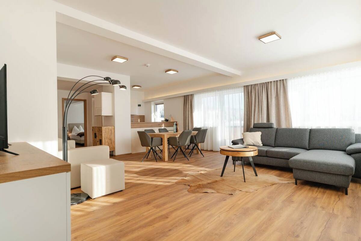 Un salon moderne comprenant un canapé, une table basse et un coin repas avec une table et des chaises.