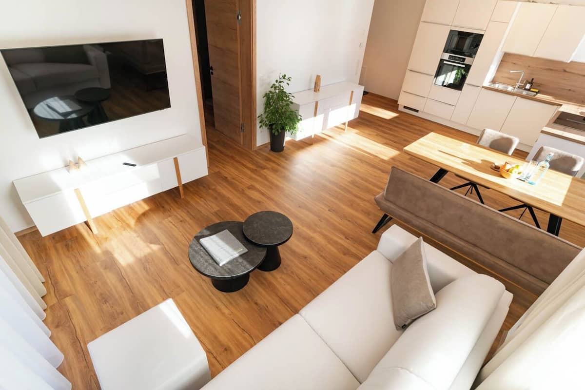 Un salon moderne doté d’un grand téléviseur, d’un canapé, d’une table basse et d’un coin repas avec une table et des chaises en bois.