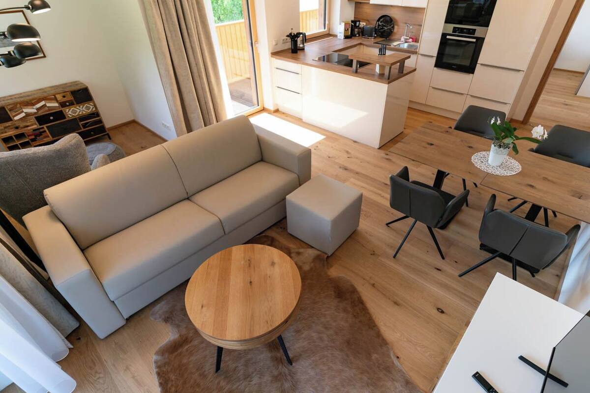Un salon moderne avec un canapé, une table basse ronde en bois et un coin repas comprenant des chaises et une petite table.