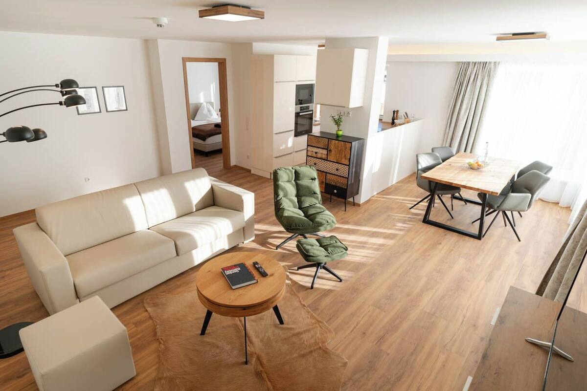 Un salon moderne avec un canapé, une table basse ronde, un fauteuil vert et une table à manger avec des chaises.