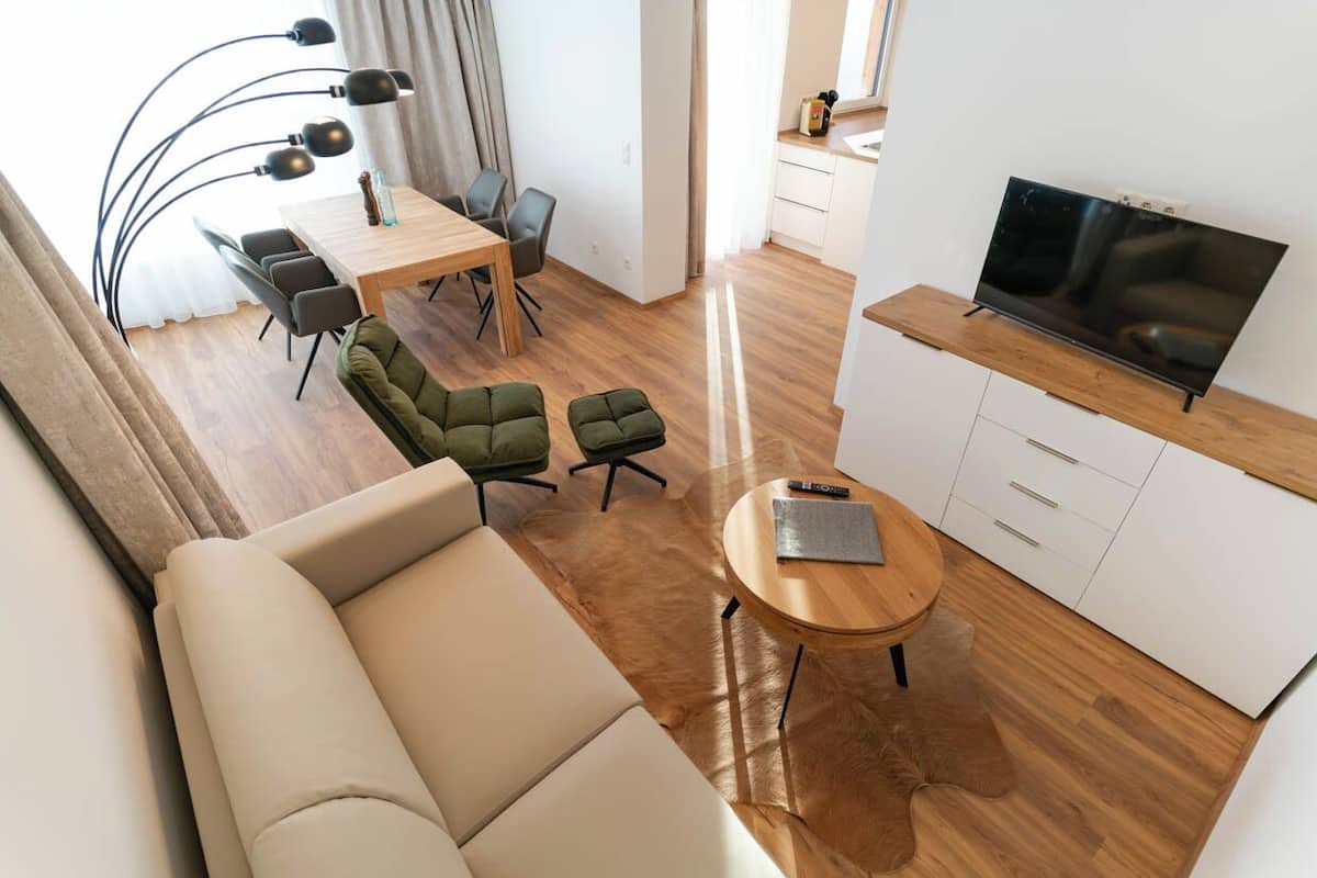 Un salon moderne comprenant un canapé, une table à manger avec des chaises, un téléviseur et un petit coin cuisine.